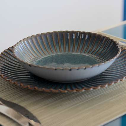 Lotus stoneware deep plate in blue glaze, styled on a matching plate